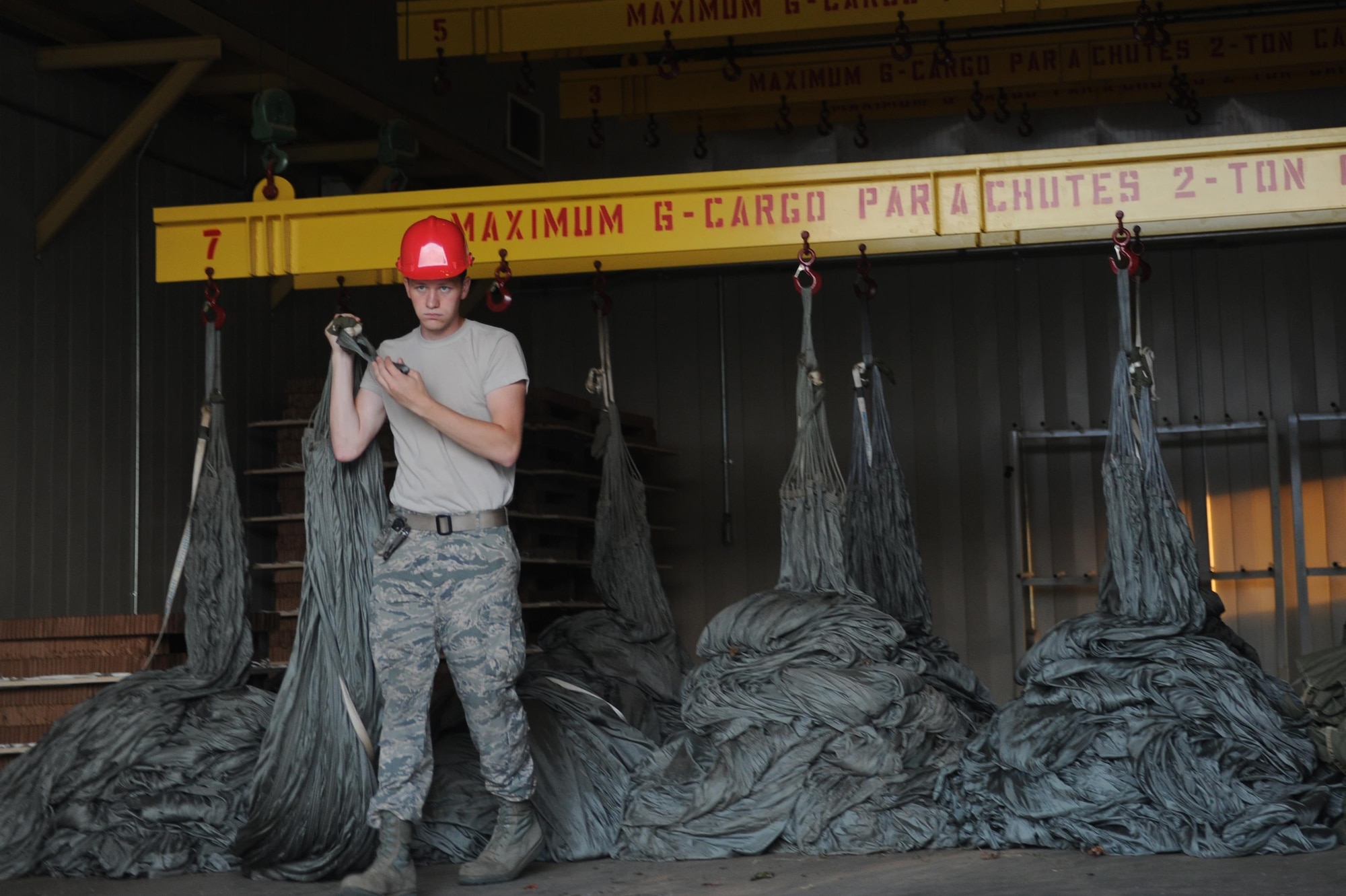 U.S Air Force Senior Airman Addison Schneider, 19th Logistics Readiness Squadron Aerial Delivery element member, removes a parachute Aug. 29, 2016, at Hangar 259 on Little Rock Air Force Base, Ark. Cargo platform parachutes are required to hang in a heated room for at least 72 hours to ensure they are completely dry.