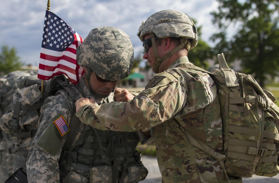 Capt. Charles Johnson assists Maj. Sam Mum, both military police in the U.S. Army Reserve assigned to the 200th Military Police Command, tighten his ruck sack before a ruck march on Fort Meade, Md., Sept. 11, 2016. Before starting the march, the unit conducted a moment of silence in honor of those lost during 9/11 and Soldiers shared their personal memories of the attacks. (U.S. Army Reserve photo by Spc. Stephanie Ramirez)