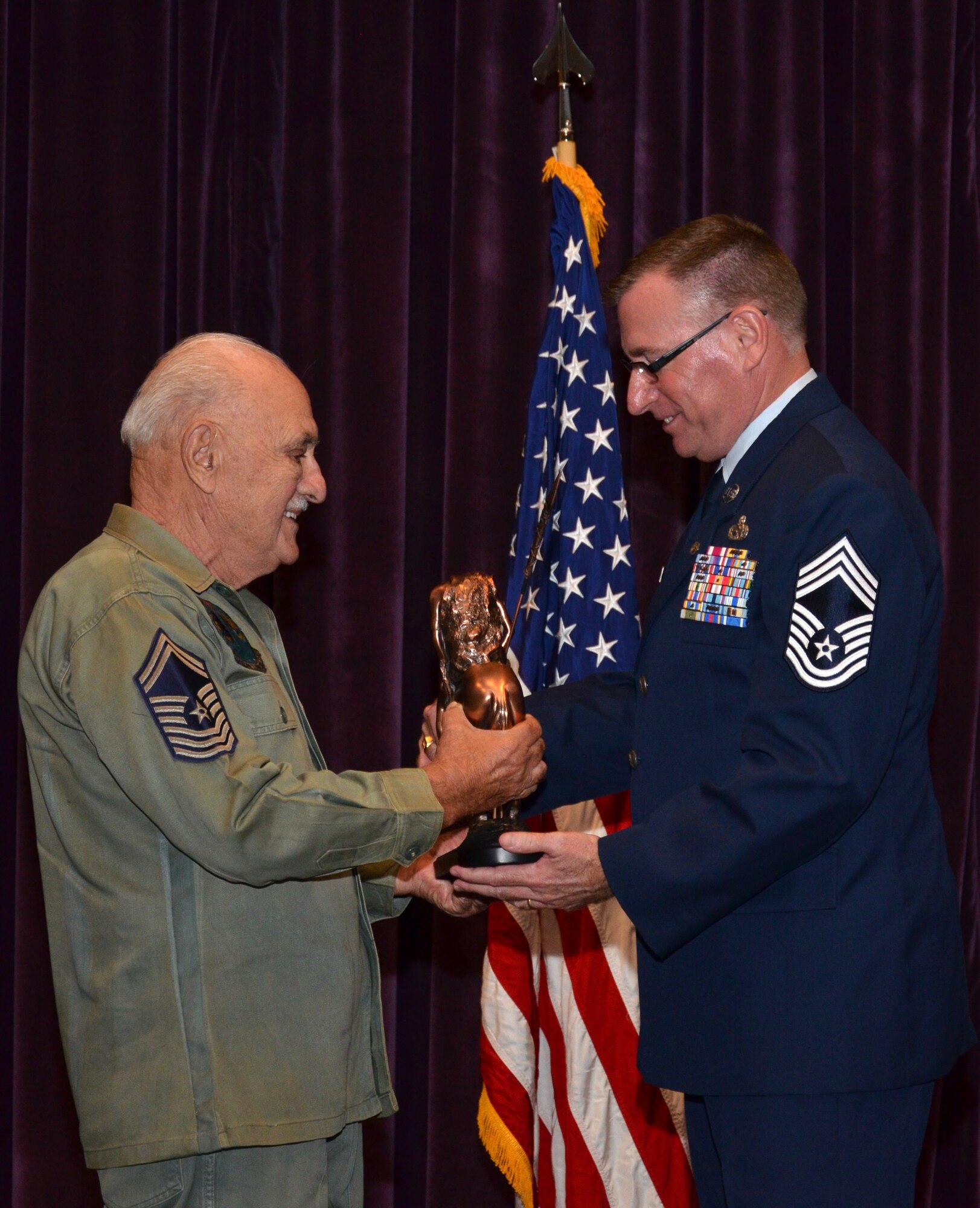 Chief Master Sgt. Joseph Pannitto passes the End of Trail statue to Chief Master Sgt. Philip Roe during Roe's retirement ceremony at Patrick Air Force Base, Fla., Sept. 10, 2016. The statue symbolizes Roe's transition into retirement after 36 years of military service. (U.S. Air Force photo by 1st Lt. Anna-Marie Wyant)