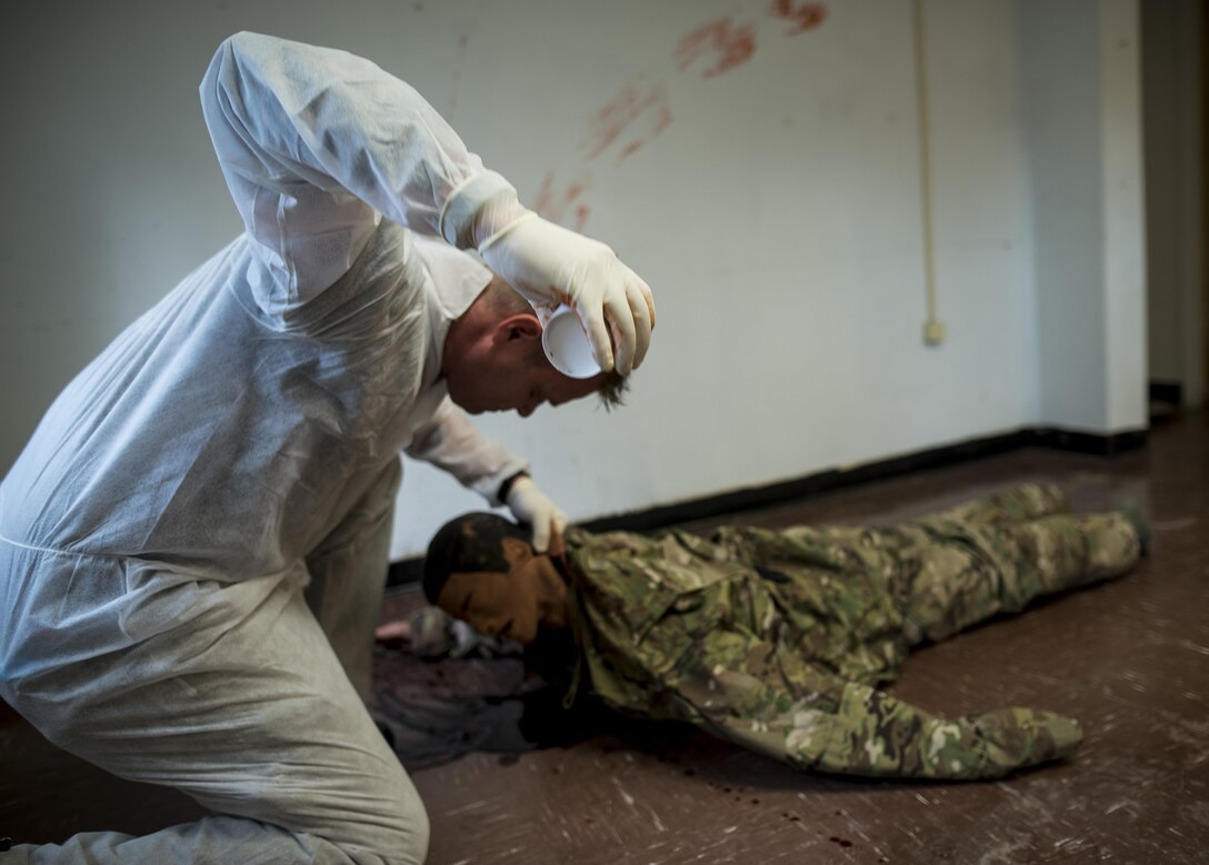 U.S. Army special agent Nathan Booth, with the 12th Military Police Detachment, Fort Eustis, Virginia, creates a "blood spurt" using a cup of fake blood underneath a dummy's head as he helps set up a training crime scene for Capital Shield 2016 at Fort Belvoir, Virginia, Sept. 13. Approximately 15 U.S. Army Reserve criminal investigative special agents trained alongside 25 active duty agents for the first time in a joint training exercise known as Capital Shield, focusing on crime scene processing, evidence management and hostage negotiations, Sept. 13-15. The reserve Soldiers participating in this year's Capital Shield are agents from the 733rd Military Police Battalion (Criminal Investigation Division), headquartered in Fort Gillem, Georgia, which reports to the 200th Military Police Command. The active duty agents belong to various offices across the Washington CID Battalion, headquartered at Fort Myer, Virginia. (U.S. Army Reserve photo by Master Sgt. Michel Sauret)