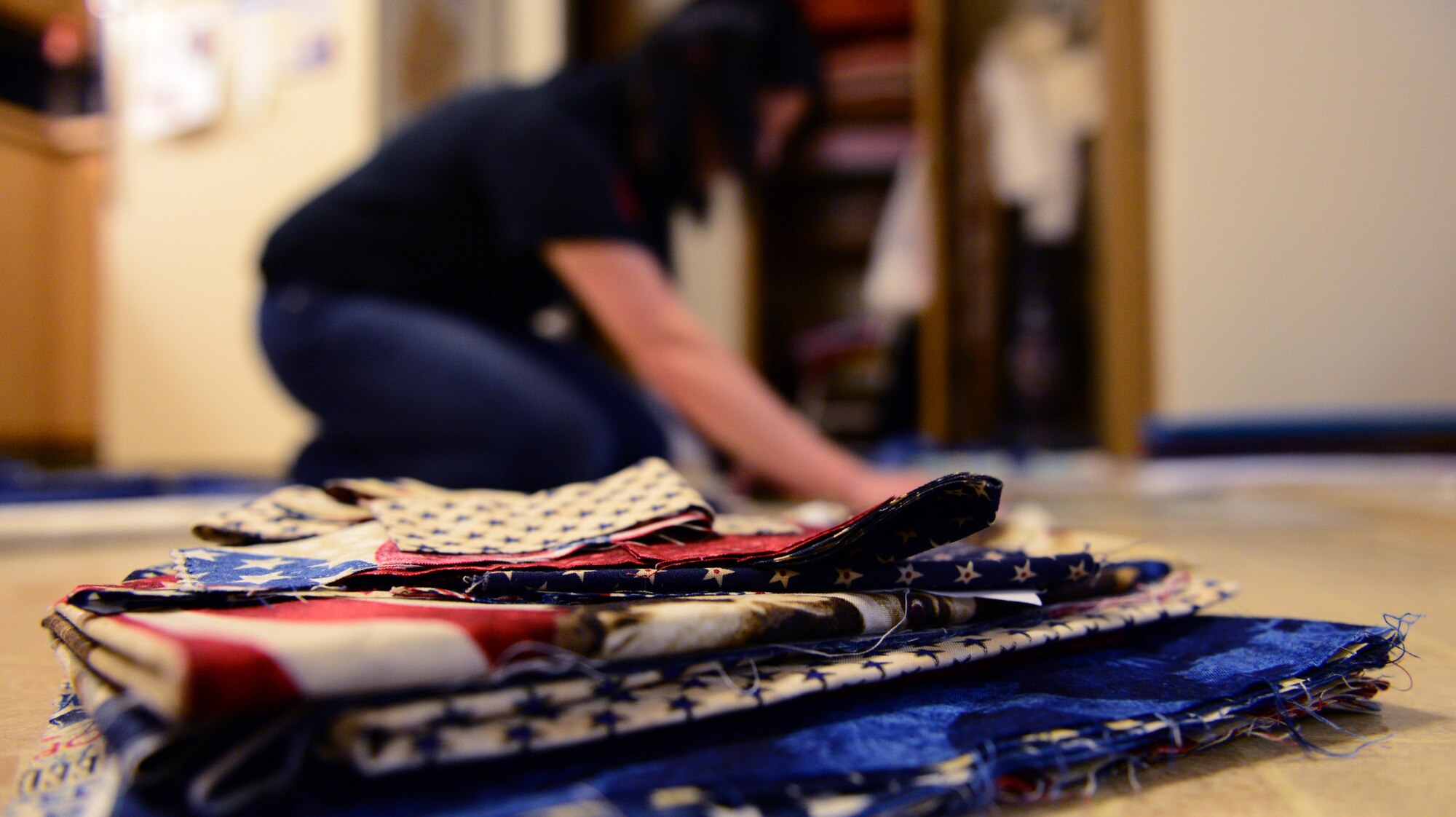 U.S. Air Force Senior Airman Karen Grinder, a 354th Contracting Squadron contracting administrator, cuts patriotic fabric Sept. 13, 2016, at her home in North Pole, Alaska. Grinder is using this fabric to work on a Quilts of Valor quilt for the Fairbanks chapter, which will donate the quilt to veterans. (U.S. Air Force photo by Airman 1st Class Cassandra Whitman)