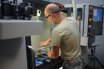 Staff Sgt. Jared Henden, 2nd Maintenance Squadron Fabrication Flight aircraft metals technology journeyman, sets up the Computer Numerical Controlled machine to build a battery tie down bracket at Barksdale Air Force Base, La., Sept. 13, 2016. The CNC is programmed plans to build different parts so Airmen don’t have to create them manually. (U.S. Air Force photo/Airman 1st Class Stuart Bright)