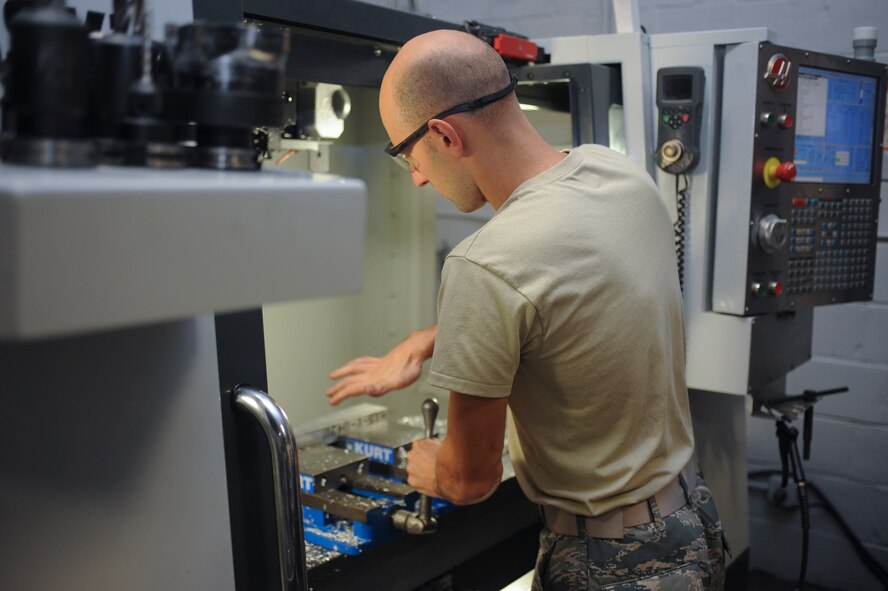 Staff Sgt. Jared Henden, 2nd Maintenance Squadron Fabrication Flight aircraft metals technology journeyman, sets up the Computer Numerical Controlled machine to build a battery tie down bracket at Barksdale Air Force Base, La., Sept. 13, 2016. The CNC is programmed plans to build different parts so Airmen don’t have to create them manually. (U.S. Air Force photo/Airman 1st Class Stuart Bright)