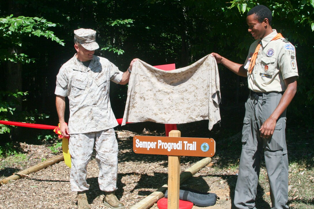 Col. Joseph Murray, commander of Marine Corps Installations National Capital Region-Marine Corps Base Quantico, and Aeris Taylor, the high school senior who oversaw the trail construction for an Eagle Scout project, unveil a sign marking the new Semper Progrendi Trail at a ceremony Sept. 14. 