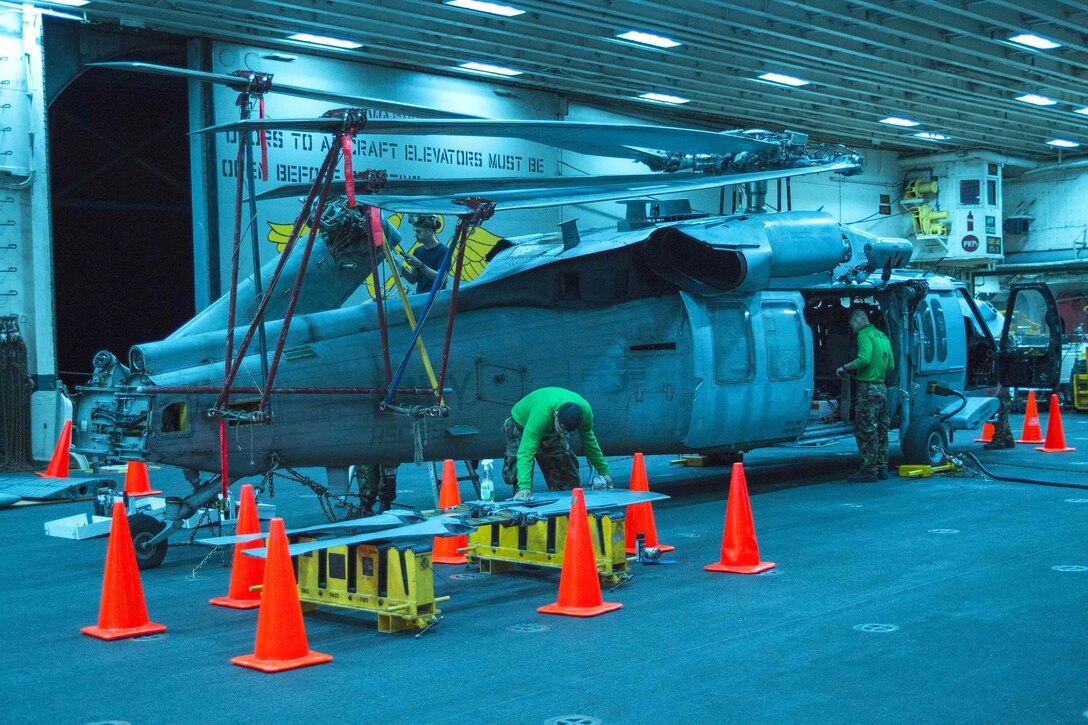 Sailors conduct maintenance on an MH-60S Seahawk in the hangar bay of the USS Bonhomme Richard in the Philippine Sea, Sept. 14, 2016. The sailors are assigned to Helicopter Sea Combat Squadron 25. The Bonhomme Richard is supporting security and stability in the Indo-Asia-Pacific region. Navy photo by Petty Officer 3rd Class William Sykes