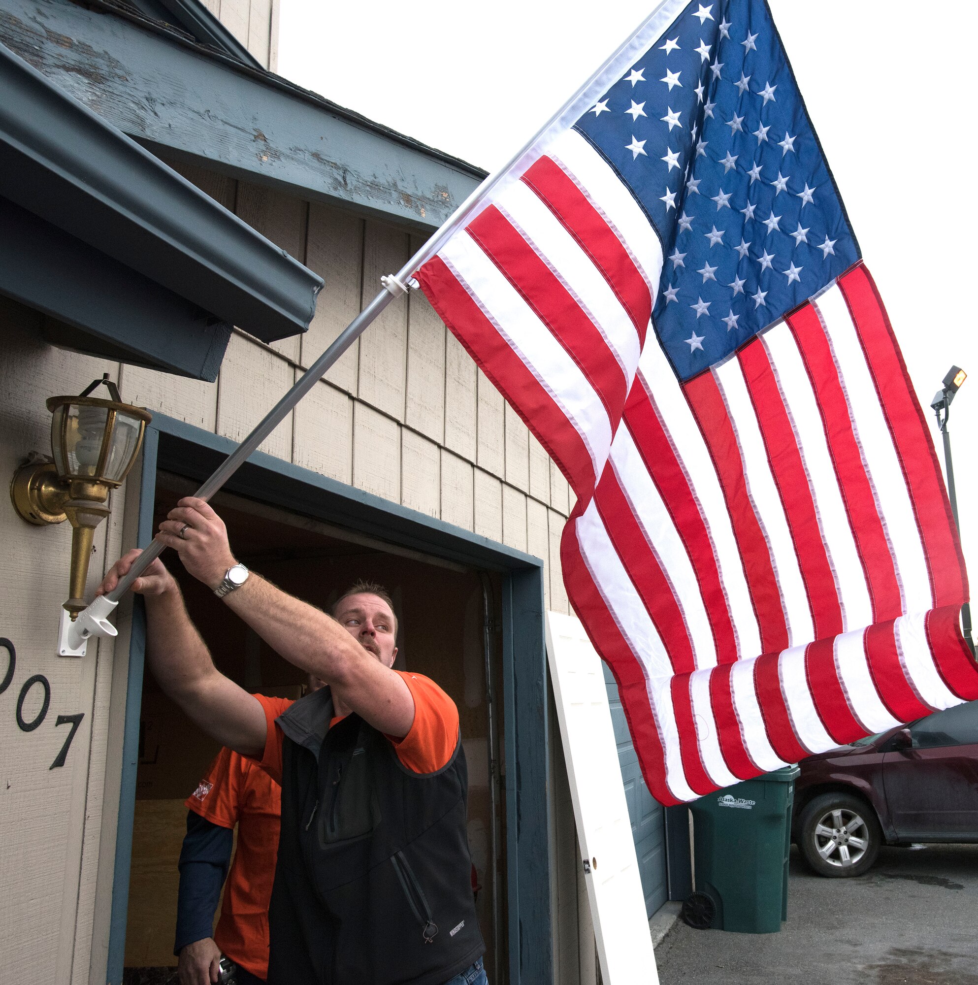 ANCHORAGE, Alaska -- A Hope Depot volunteer affixes an American flag to the residence of Staff Sgt. Sequoya Joseph, a personnelist with the Alaska Air National Guard's 176th Force Support Flight, here Sept. 14, 2016. About 50 volunteers came together to renovate Joseph's home. The effort was the result of a partnership between Home Depot's annual Celebration of Service Campaign and the non-profit That Others May Live Foundation. National Guard photo by Maj. John Callahan.
