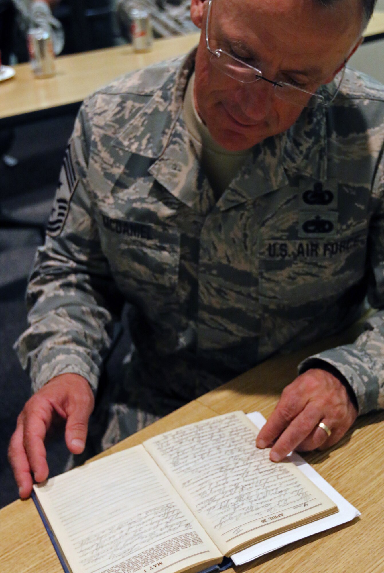 173rd Fighter Wing Command Chief Master Sgt. Mark McDaniel looks at Lt. David R. Kingsley’s handwritten journal from WWII, Aug. 31, 2016. WWII veteran Joe Rollison, who married into the Kingsley family and survives his wife of 56 years, donated the historic item to the base during his visit. (U.S. Air National Guard photo by Tech. Sgt. Jefferson Thompson)