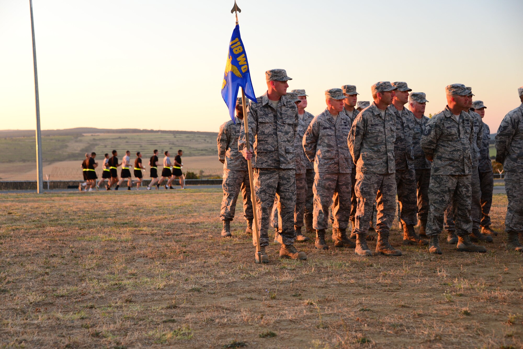 Airmen from the 118th Mission Support Group, Tennessee Air National Guard, stand at parade rest at a sunrise formation as Army Soldiers do their morning PT Aug. 15, 2016, at Novo Selo Training Area, Bulgaria.  Tennessee National Guard Soldiers and Airmen were on rotations to complete thier portions of projects as part of Operation Resolute Castle 16, an ongoing operation of military construction to build up Eastern European base infrastructure and help strengthen ties between Tennessee's state partnership with Bulgaria. (U.S. Air National Guard photo by Master Sgt. Kendra M. Owenby, 134 ARW Public Affairs)