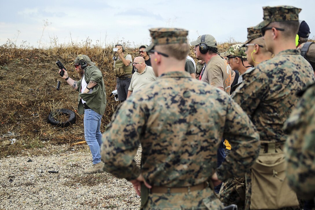 Instructor Zero, a chief instructor with Spartan 360 Tactical Defense, performs a speed reload as Marines with Special Purpose Marine Air-Ground Task Force Crisis Response-Africa watch during a live-fire range near Naval Air Station Sigonella, Italy, Sept. 10, 2016.  Marines with SPMAGTF-CR-AF took an advanced shooting course with Instructor Zero, who went over fundamentals and tactics of firing a handgun.  (U.S. Marine Corps photo by Cpl. Alexander Mitchell/released)