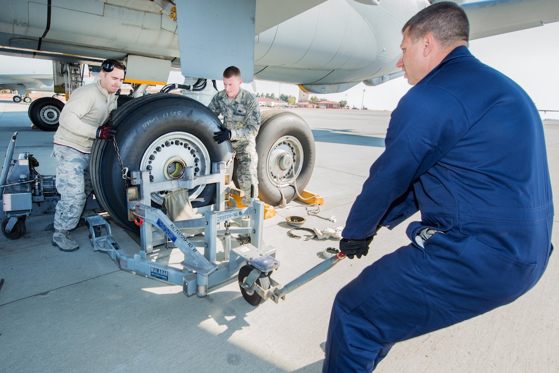 Air Force Chief Master Sgt. Steve Nichols, right, command chief of the 60th Air Mobility Wing, Air Force Senior Airman Joseph Eidson, left, and Air Force Staff Sgt. Elliott Bullis, center, use an aircraft tire dolly to lift and remove a tire from a KC-10 Extender during the "Works With Airmen" program at Travis Air Force Base, Calif., Sept. 9, 2016. Eidson and Bullis are crew chiefs assigned to the 660th Aircraft Maintenance Squadron. Air Force photo by Louis Briscese