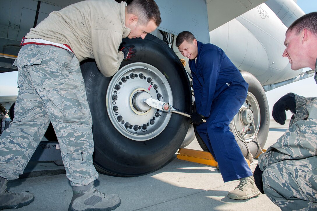 Air Force Senior Airman Joseph Eidson, left, holds the tire on a KC-10 Extender while Air Force Chief Master Sgt. Steve Nichols, center, command chief of the 60th Air Mobility Wing, torques the wheel nut during the "Works With Airmen" program at Travis Air Force Base, Calif., Sept. 9, 2016. Eidson is a crew chief assigned to the 660th Aircraft Maintenance Squadron. Air Force photo by Louis Briscese
