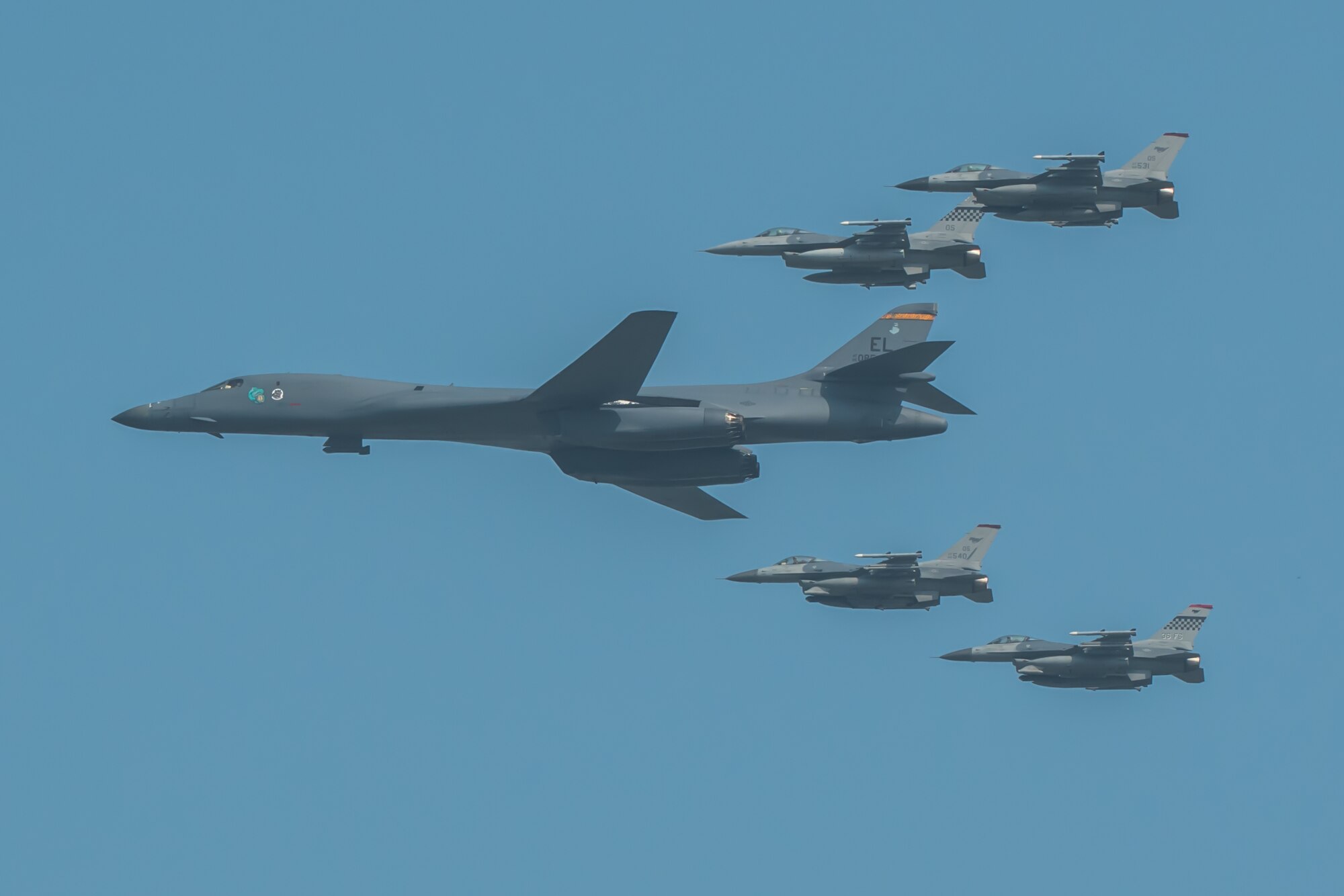 A U.S. Air Force B-1B Lancer, escorted by U.S. Air Force F-16 Fighting Falcons, performs a flyover over Osan Air Base, ROK, Sept. 13, 2016. The flyover highlighted the close cooperation between American and ROK military forces that keeps them ready to respond at any time to threats to stability and security. The B-1s are currently assigned to Andersen Air Force Base, Guam. (U.S. Air Force photo by Senior Airman Dillian Bamman)