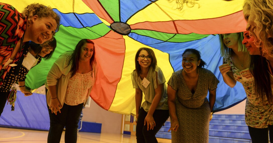 Participants in the 2016 Child and Youth Programs Training Conference for the U.K. hide under a parachute during the Parachute Play class Sept. 10, 2016, on RAF Mildenhall, England. The conference was held to provide childcare providers, administrators, managers and cooks who worked in Child Development Centers and Youth Centers across the U.K. with mandatory annual training. (U.S. Air Force photo by Staff Sgt. Micaiah Anthony)