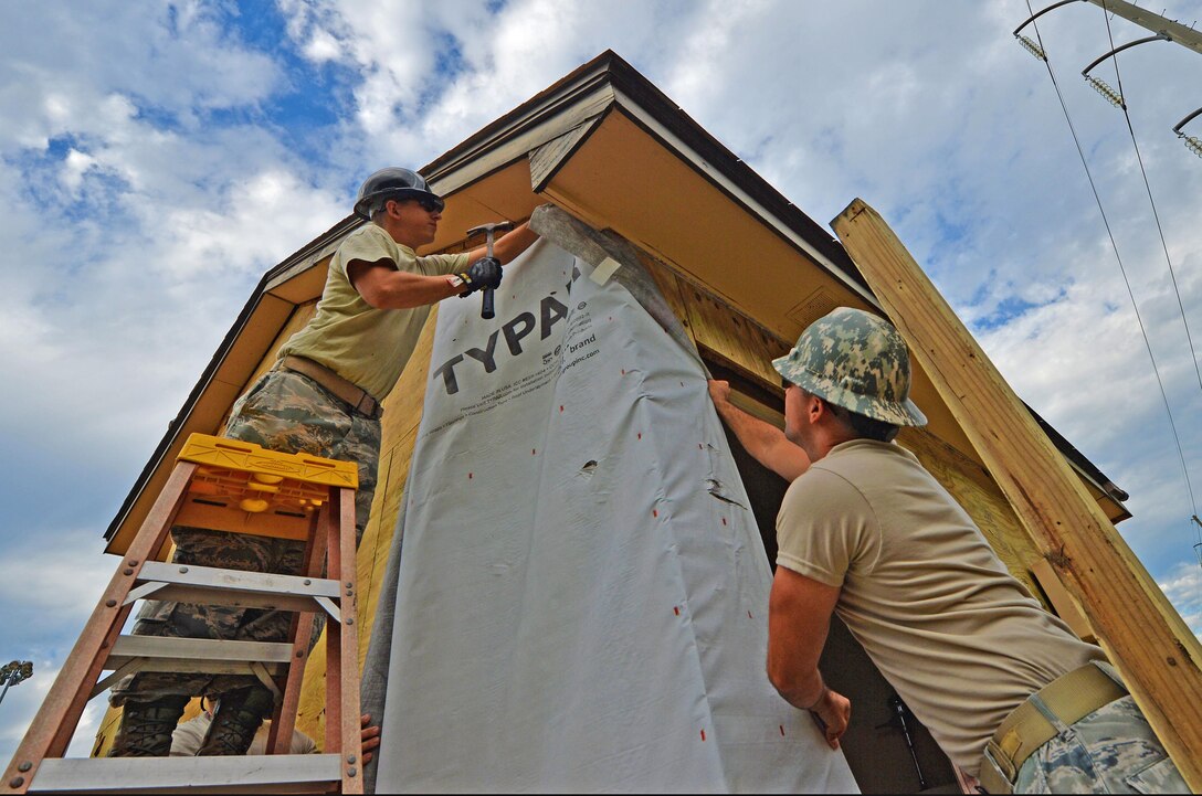 Staff Sgt. Michael Kitzler and Tech. Sgt. Nate Dowling, structural specialists with the 556th RED HORSE, secure house wrap around the softball field press box at Hurlburt Field Fla., Sept. 12, 2016. House wrap is used as insulation to keep moisture out of an infrastructure. (U.S. Air Force photo by Senior Airman Andrea Posey)