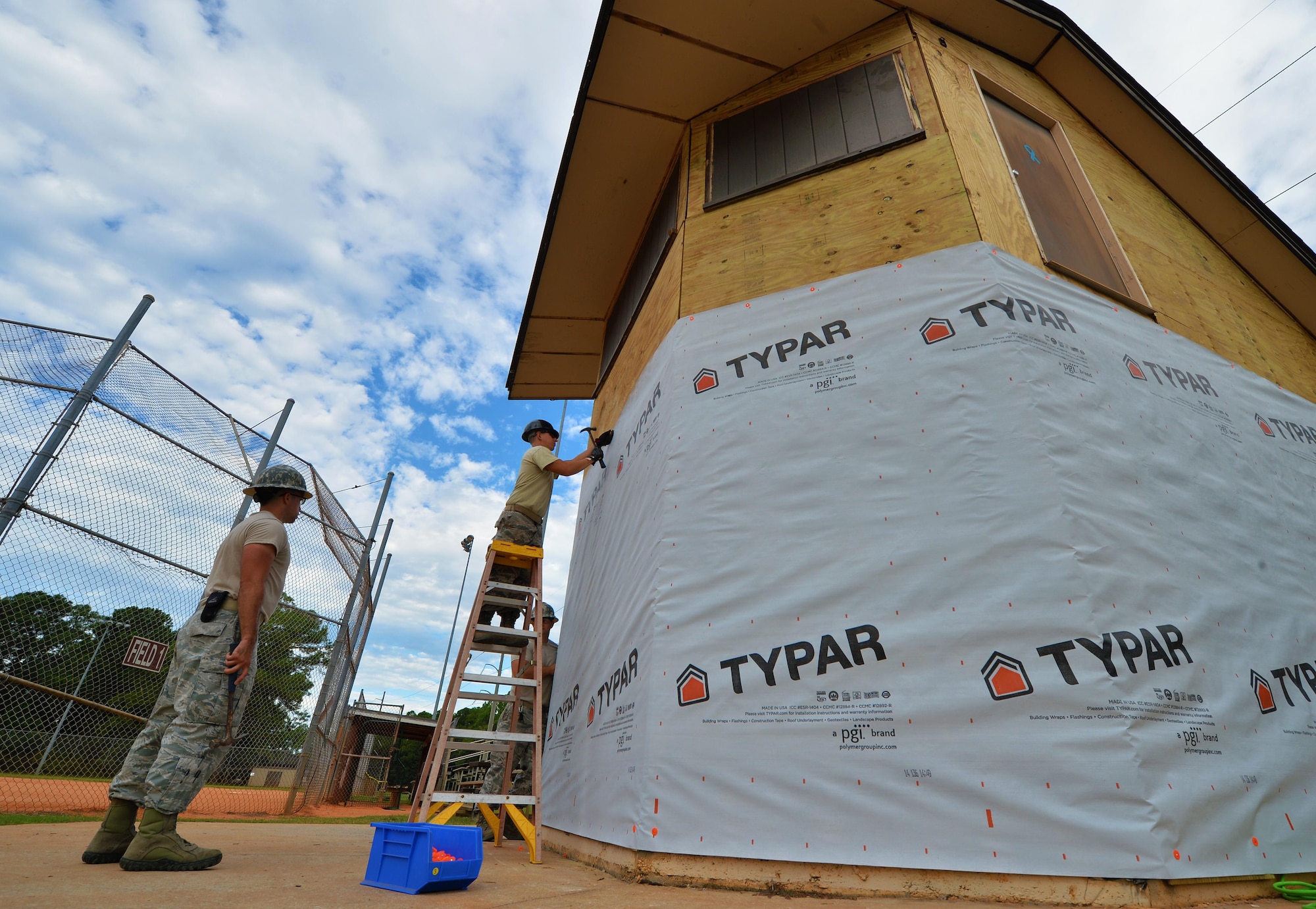 Civil engineer Airmen with the 556th RED HORSE secure house wrap around the softball field press box at Hurlburt Field Fla., Sept. 12, 2016. The civil engineers are renovating the 20-year-old building to counteract water and moisture damage. (U.S. Air Force photo by Senior Airman Andrea Posey)