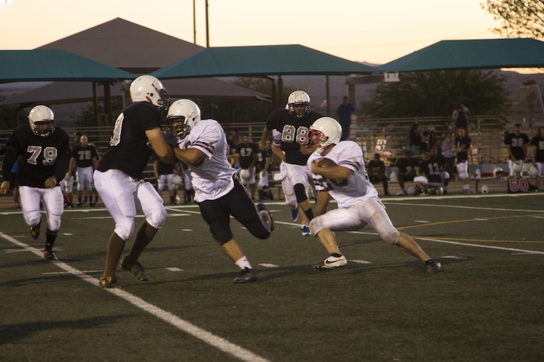 A Marine with the 1st Tank Battalion football team blocks a player from the Robert E. Bush Naval Hospital Twentynine Palms and Marine Corps Communication-Electronics School’s joint team during the Marine Corps Community Services Sports hosted Football Jamboree at Felix Field, Sept. 14, 2016. The event is held annually and functions as a pre-season game for the Intramural Tackle Football League. (Official Marine Corps photo by Cpl. Medina Ayala-Lo/Released)