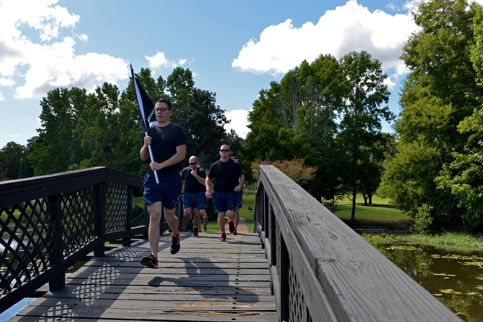 Team Shaw members run with a POW/MIA flag during a 24-hour National POW/MIA Recognition Day vigil run at Shaw Air Force Base, S.C., Sept. 15, 2016. During the run, service members kept the flag in motion throughout the 24-hours by handing it off to the next participant. (U.S. Air Force photo by Airman 1st Class Destinee Sweeney)