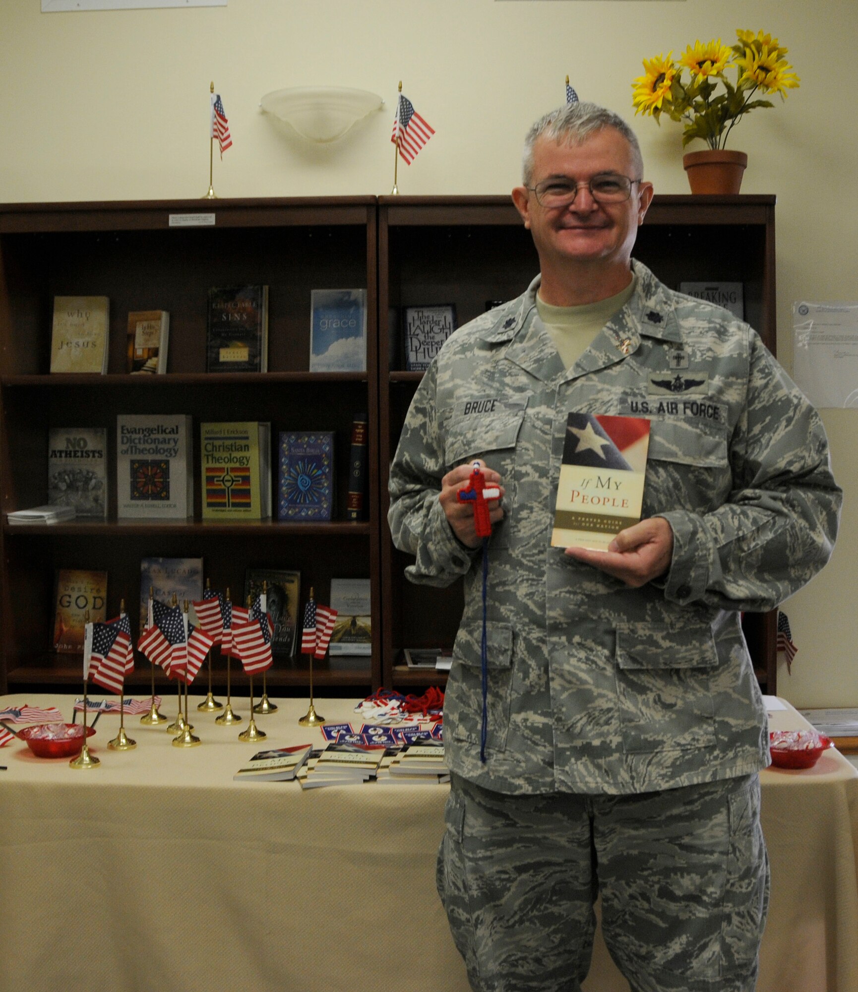 Chaplain (Lt. Col.) Jeffery Bruce poses with an “If my People” prayer book and a yarn necklace shaped into a cross. These items were given to Airmen who attended the 9/11 remembrance service in the base chapel Sept. 11. The service was held to honor the 3,000 victims killed in the 9/11 terrorist attacks. (U.S. Air Force photo by Senior Airman Aja Heiden)