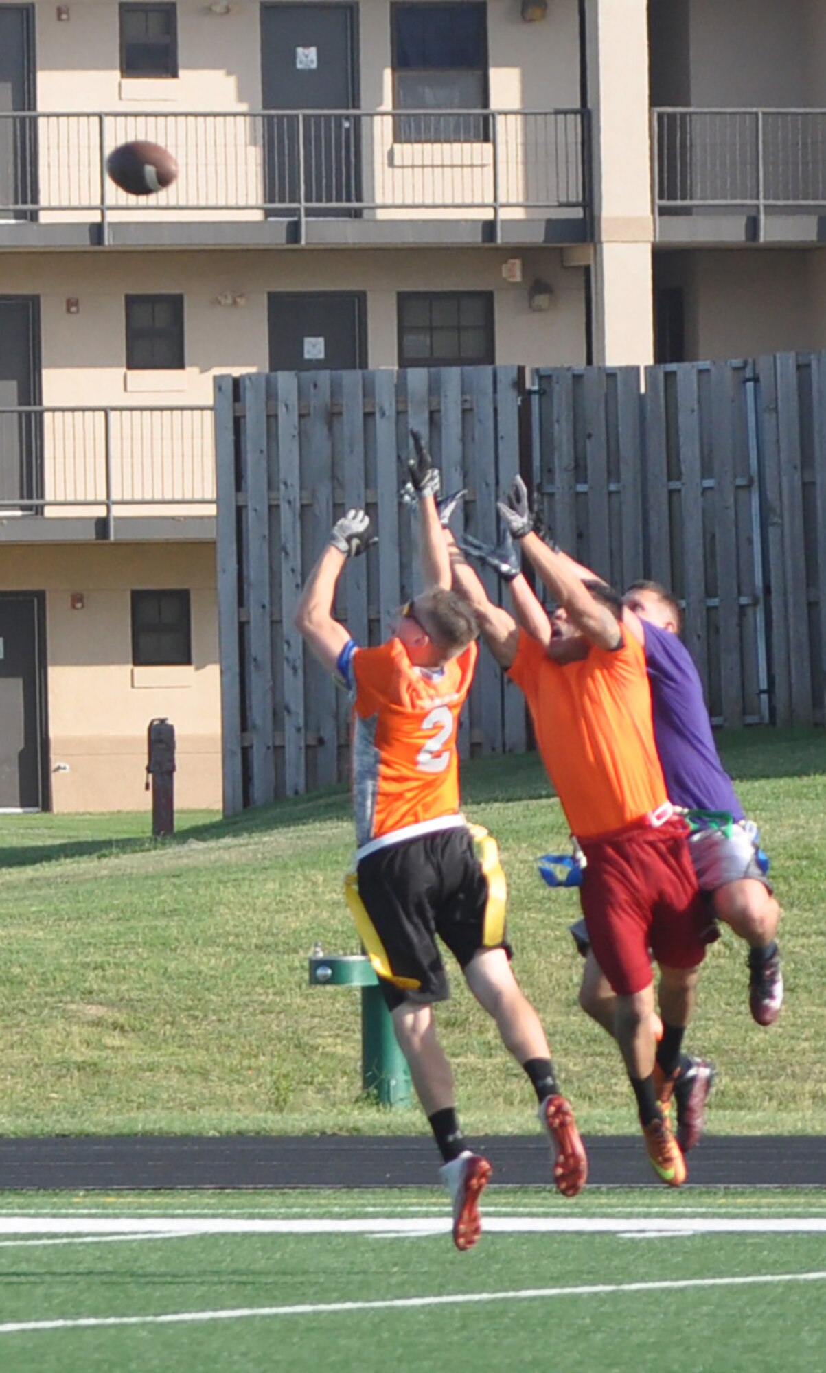 552nd MXS defenders Johnny Kammunkun, left, and Eric Zach, also in orange, zero in on a long bomb during a Sept. 8 flag football game. Despite double coverage, 552nd ACNS receiver Donovan Garcia stayed alert as the ball bobbled off the defenders’ hands, floating into Garcia’s arms. He ran 5 yards alone for a TD. (Air Force photo by John Parker)