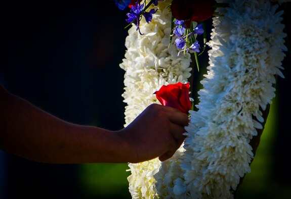 A Rancho High School Junior ROTC cadet places a red rose in a white wreath at the Prisoner of War/Missing in Action Ceremony at Freedom Park on Nellis Air Force Base, Nev., Sept. 16, 2016. Cadets placed a red rose on the white wreath for the Nevada deceased prisoners of war or military members missing in action to represent respect for those individuals. (U.S. Air Force photo by Airman 1st Class Nathan Byrnes)