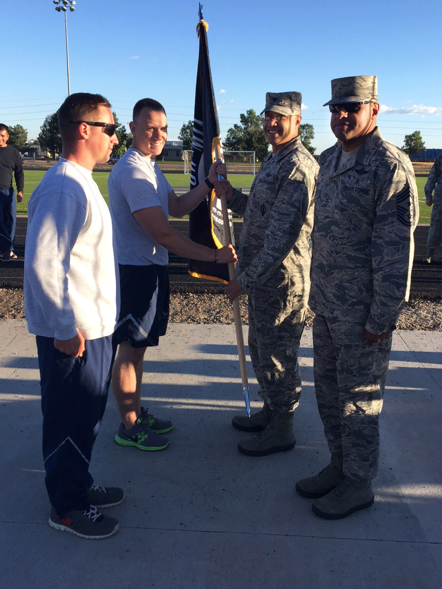 U.S. Air Force Col. David Miller Jr., 460th Space Wing commander, passes the POW/MIA flag to -–Staff Sgt. Jacob Frierdich, 460th Security Forces Squadron unit deployment manager to kick off a 24-hour memorial run Sept. 15, 2016, at an outdoor track on Buckley Air Force Base, Colo. The run served as remembrance of those servicemen and women who never returned home. (U.S. Air Force photo by Airman 1st Class Gabrielle Spradling/Released)