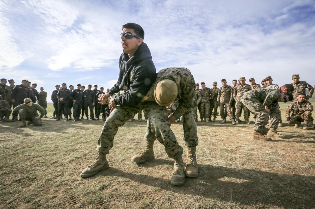Marine Corps Cpl. Ezequiel Silva, left, demonstrates mechanical advantage control hold techniques to Mongolian troops during Nonlethal Executive Seminar 2016 at Five Hills Training Area, Mongolia, Sept. 16, 2016. The event is a regularly scheduled leadership seminar and field training exercise hosted by various Asia-Pacific nations. Marine Corps photo by Cpl. Jonathan E. LopezCruet