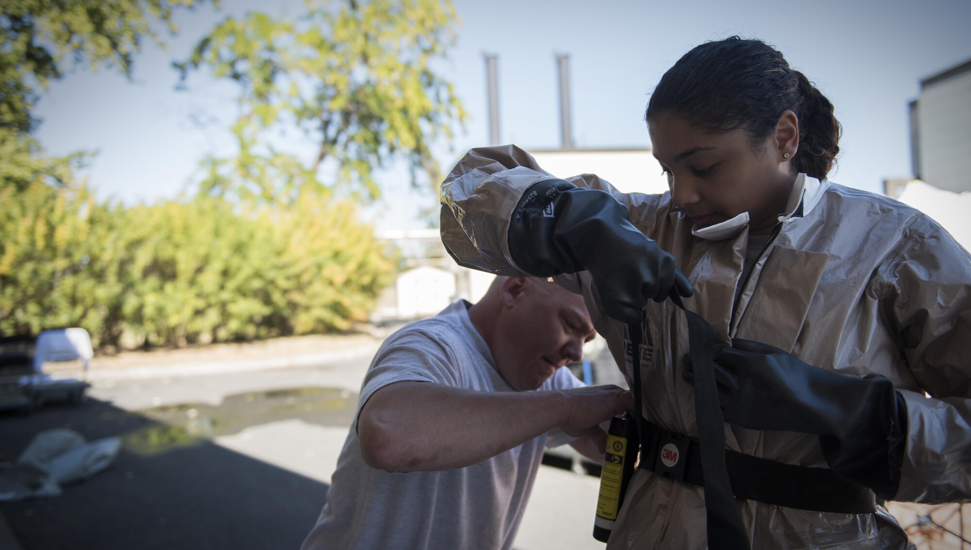 Capt. Dan Norman, 92nd Medical Operational Support Squadron physician’s assistant, helps Senior Airman Janeen Gray, 92nd Medical Operational Support Squadron Medical Administration, don her protective equipment during a mock decontamination training exercise Sept. 16, 2016, at Fairchild Air Force Base, Wash. The training is biannual and helps the In-Place Patient Decontamination team’s role of effectively collaborating with the manpower, security and triage teams in the case a chemical, biological, radiological or nuclear event occurs. (U.S. Air Force photo/Airman 1st Class Sean Campbell)