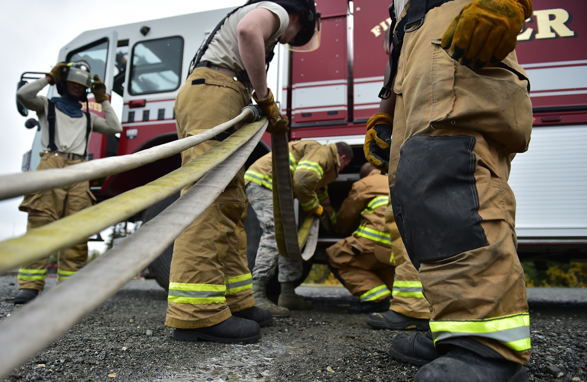 Fire protection specialist Airmen assigned to the 673rd Civil Engineer Squadron roll up water hoses after firefighter training on a simulated aircraft fire at Joint Base Elmendorf-Richardson, Alaska, Wednesday, Sept. 14, 2016.  Aircraft live fire training is conducted periodically throughout the year at JBER to ensure Airmen are prepared to combat aircraft fuel fires. 