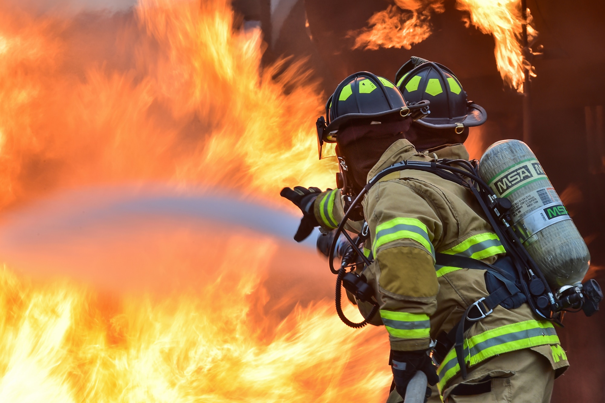Fire protection specialists Tech Sgt. Sean Armstrong, and Senior Airman Larry Kyles, assigned to the 673rd Civil Engineer Squadron, perform firefighter training on a simulated aircraft fire at Joint Base Elmendorf-Richardson, Alaska, Wednesday, Sept. 14, 2016.  Aircraft live fire training is conducted periodically throughout the year at JBER to ensure Airmen are prepared to combat aircraft fuel fires.