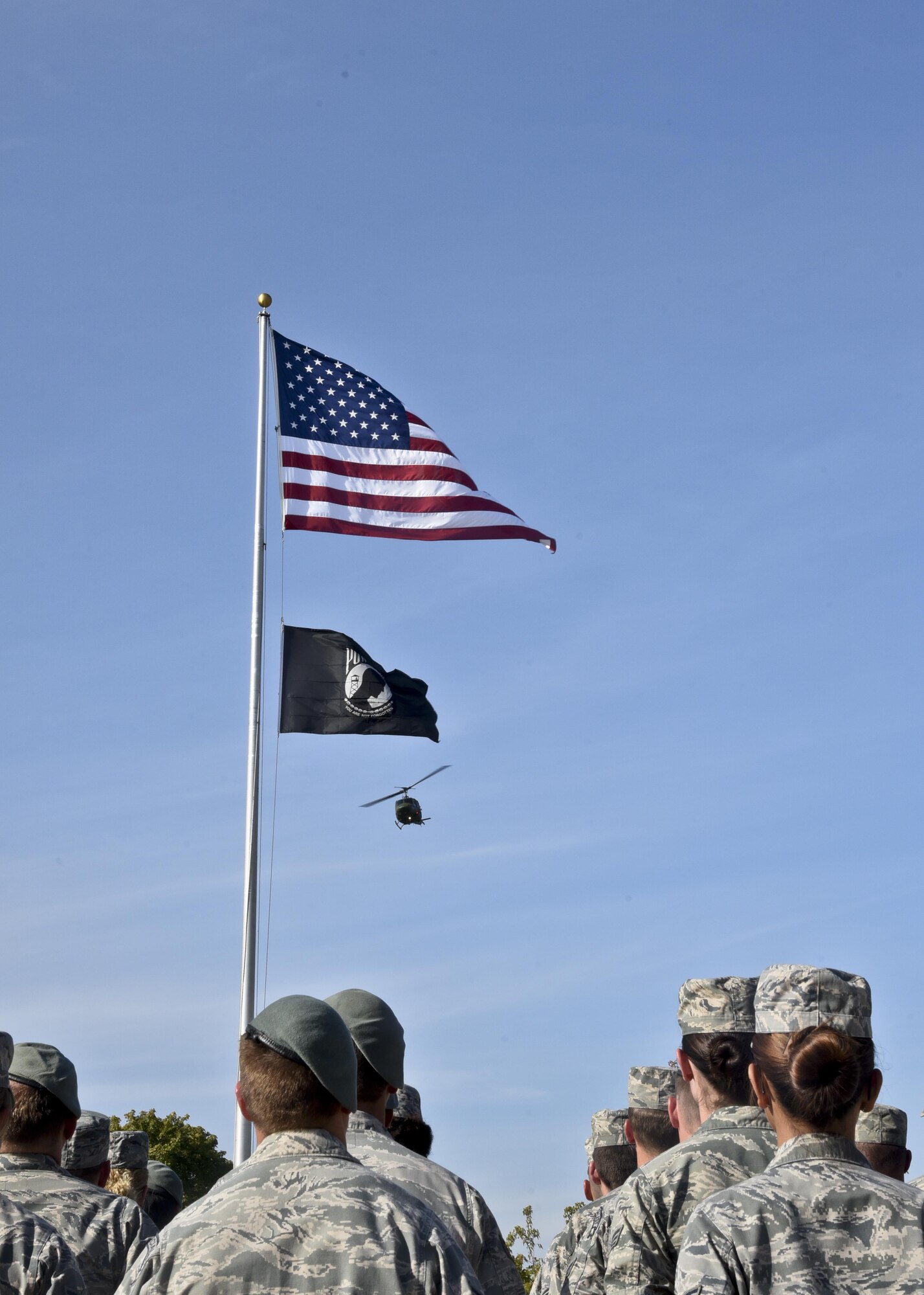 A UH-1 helicopter displaying the American flag and the POW/MIA flag does a fly over during the POW/MIA recognition day ceremony Sept. 16, 2016, at Fairchild Air Force Base, Wash. The ceremony honored American prisoners of war and those missing in action. (U.S. Air Force photo/Airman 1st Class Taylor Shelton)