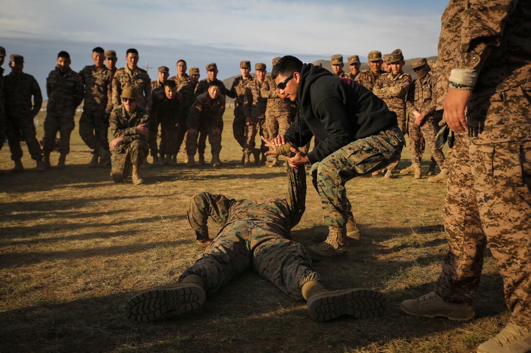 U.S. Marine Cpl. Ezequiel Silva demonstrates mechanical advantage control holds techniques to Mongolian Armed Forces soldiers and Mongolian National Police during Non-Lethal Executive Seminar (NOLES) 2016 at the Five Hills Training Area, Mongolia, Sept. 16, 2016. Silva is a military police Marine with 3rd Law Enforcement Battalion, III Marine Expeditionary Force. Mongolian soldiers and police learned mechanical advantage control holds techniques as an additional non-lethal option when apprehending suspects. NOLES is a regularly scheduled field training exercise and leadership seminar hosted annually by various nations throughout Asia Pacific. (U.S. Marine Corps photo by Cpl. Jonathan E. LopezCruet)