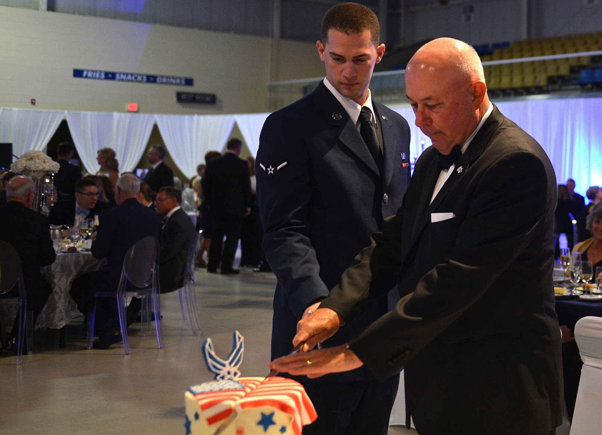 U.S. Air Force Airman Gage Hunwardsen, 20th Comptroller Squadron financial service technician, cuts the Air Force Ball cake with Retired Gen. T. Michael Moseley, previous 19th Air Force chief of staff, during the Air Force Ball at the Sumter Civic Center, Sumter, S.C., Sept. 16, 2016. The cake is cut with a ceremonial sabre by the lowest and highest-ranking Airman in attendance. (U.S. Air Force photo by Airman 1st Class Christopher Maldonado)