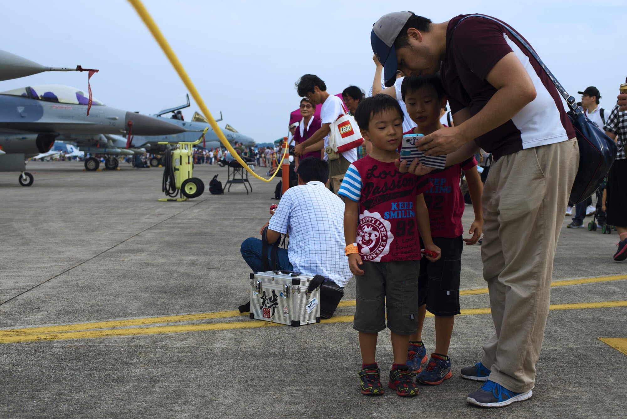 A father shows his sons a photo at the 2016 Friendship Festival on 17 Sept. 2016 at Yokota Air Base, Japan. The Friendship Festival is an annual event for the local community. (U.S. Air Force photo by Airman 1st Class Donald Hudson/Released)