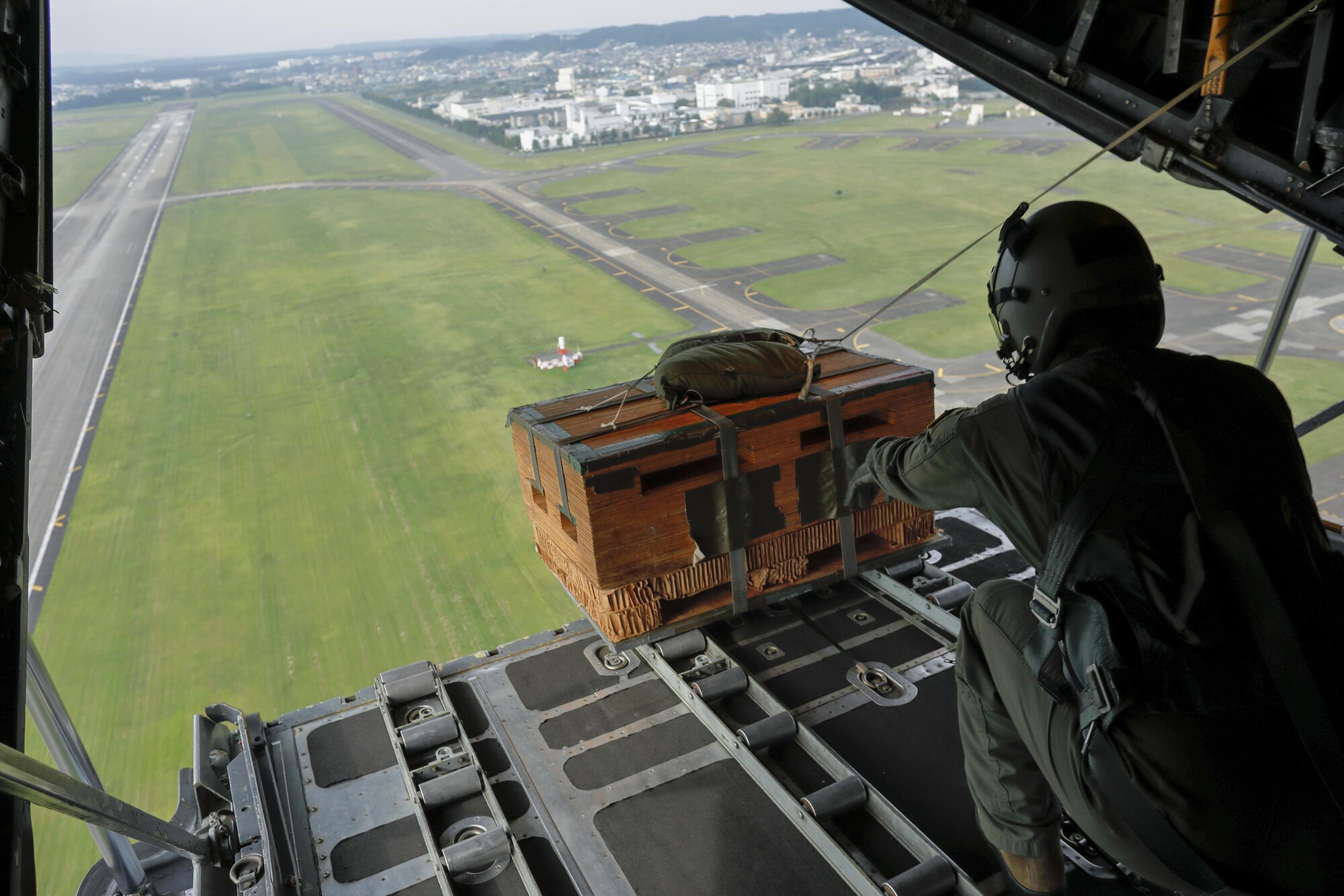 Senior Airman Andrew Fox, 36th Airlift Squadron C-130H loadmaster, drops a low-cast, low-altitude bundle over Yokota Air Base, Japan, Sept. 17, 2016, during the 2016 Friendship Festival. The 36th Airlift Squadron demonstrated their airdrop capabilities to a crowd of tens of thousands. (U.S. Air Force photo by Yasuo Osakabe/Released) 