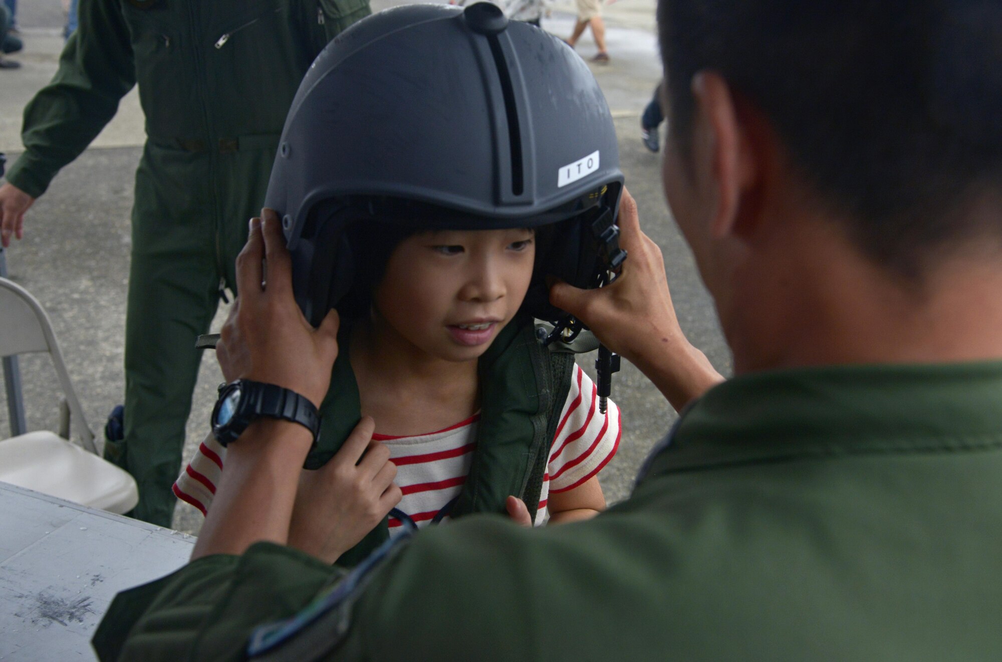 Japan Air Self-Defense Force Capt. Takeshi Itoh, 1st Tatical Airlift Wing 401st Squadron C-130 Hercules Navigator, places a helmet on a child during the Friendship Festival at Yokota Air Base, Japan, Sept. 18, 2016. The event also included live performances from bands, a strongman competition, dances, ariel demonstrations, static displays and military working dog demonstrations. (U.S. Air Force photo by Senior Airman David Owsianka/Released)