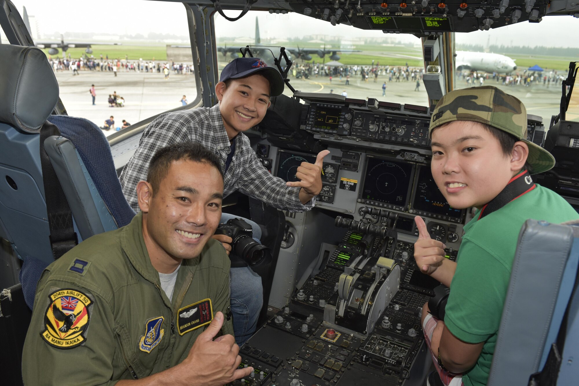 Capt. Brandon Chang, 204th Airlift Squadron C-17 Globemaster III pilot, poses for a photo with Japanese festivalgoers during the 2016 Friendship Festival at Yokota Air Base, Japan, Sept. 18, 2016. The festival is held annually and offers the US military on base a chance to share their work and culture with their off-base neighbors. (U.S. Air Force photo by Machiko Imai/Released)