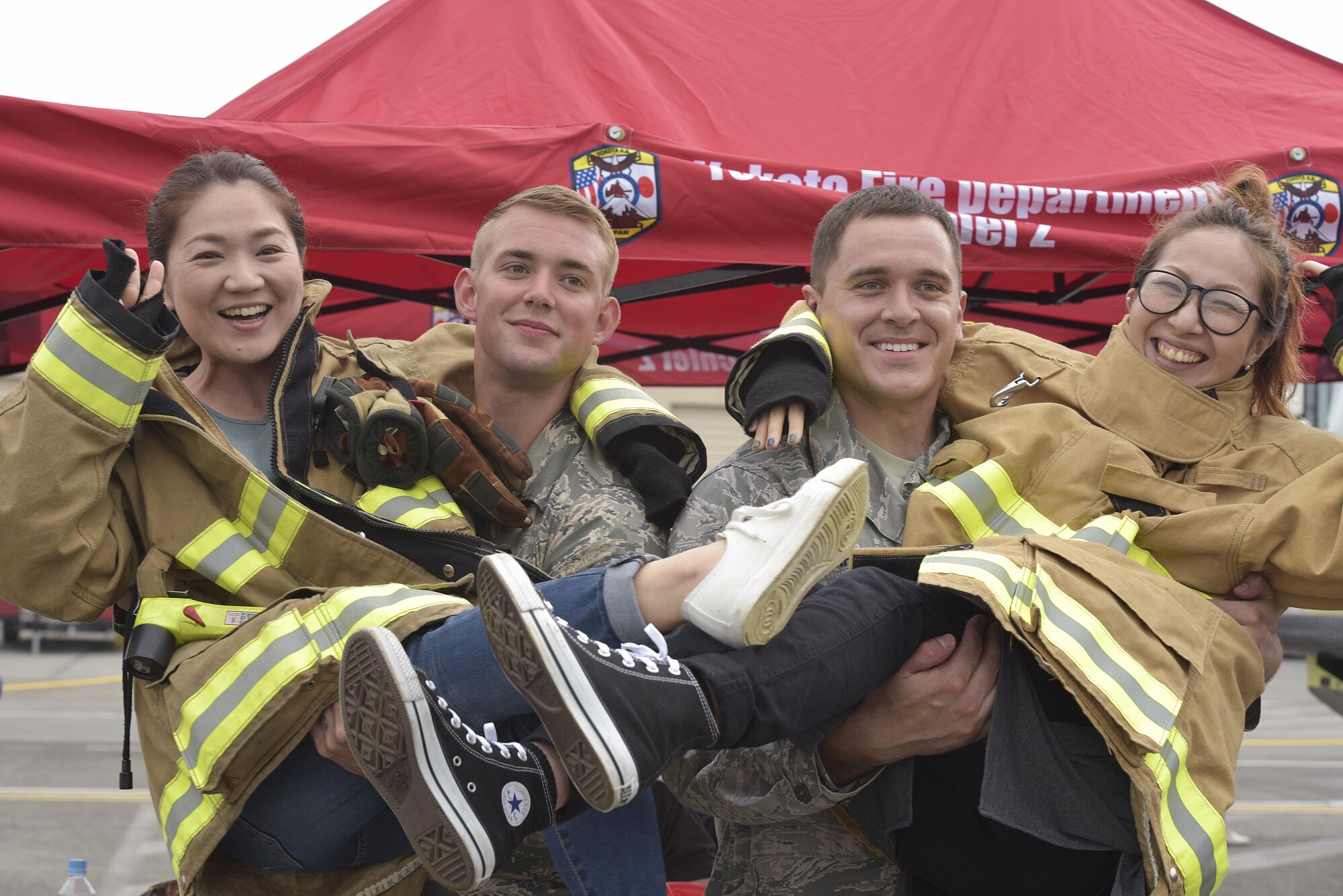 (Right to left) Staff Sgt. Bryan Schroeder and Senior Airman Thomas Smith, both from the 374th Civil Engineer Squadron fire department, pose for a photo with Japanese festivalgoers during the 2016 Friendship Festival at Yokota Air Base, Japan, Sept. 18, 2016. The festival hosted food vendors, static aircraft displays, live entertainment and military and government demonstrations. (U.S. Air Force photo by Machiko Imai/Released)