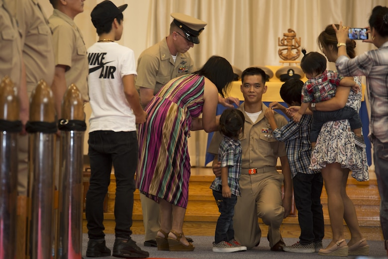 U.S. Navy Chief Petty Officer Johnerikson Angeles, chief aviation machinist mate with Aircraft Intermediate Maintenance Detachment, kneels while being pinned during a promotion ceremony in the Marine Memorial Chapel at Marine Corps Air Station Iwakuni, Japan, Sept. 16, 2016. Angeles chose to be pinned by his wife and kids in appreciation of their support for his service as a Sailor. (U.S. Marine Corps photo by Lance Cpl. Joseph Abrego)
