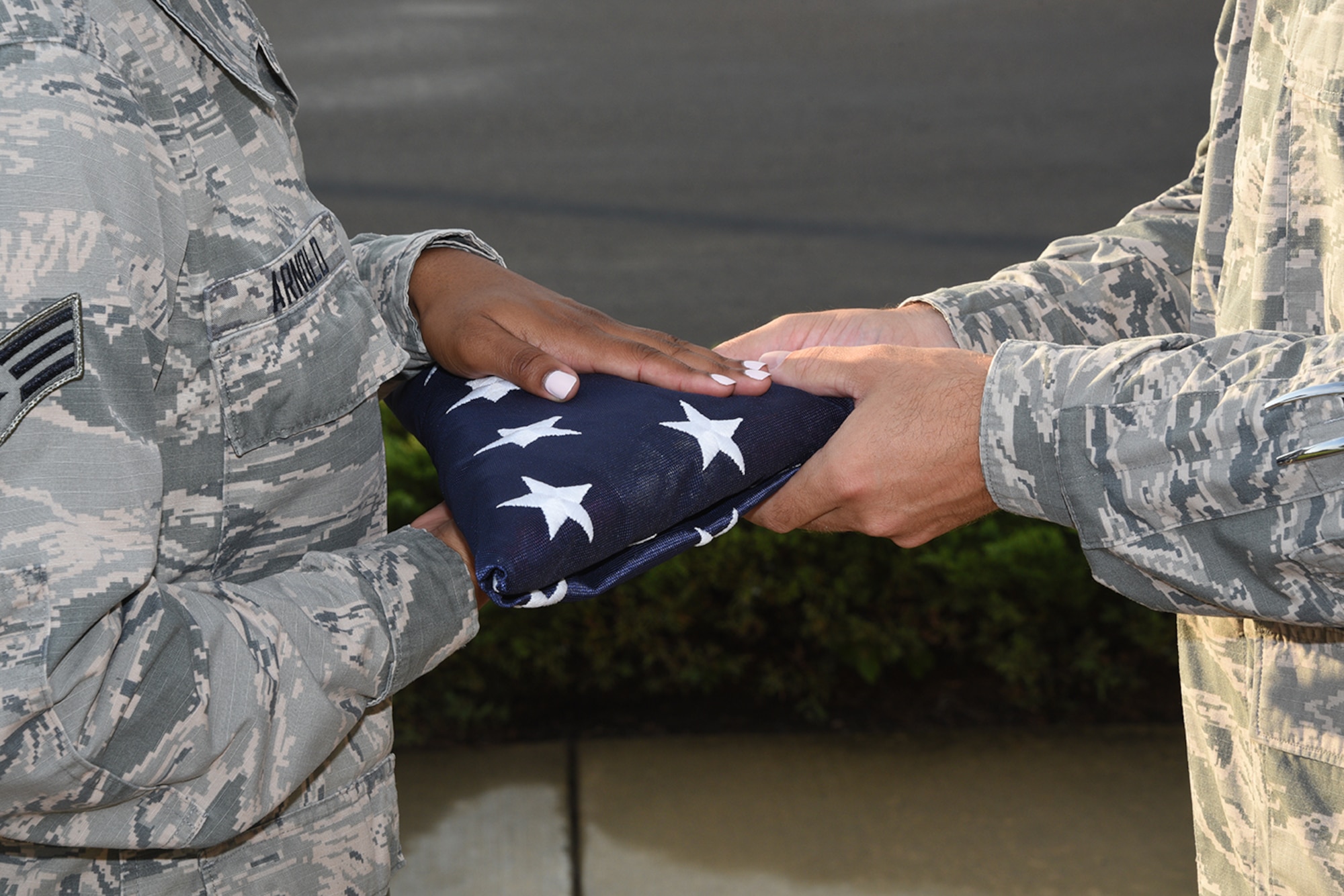 Senior Airman Chelcee Arnold passes the American Flag to Senior Master Matthew Smith at the Retreat ceremony at the 164th Airlift Wing in Memphis, Tenn on August 7, 2016. (U.S. Air National Guard photo by Master Sergeant Danial Mosher/Released)