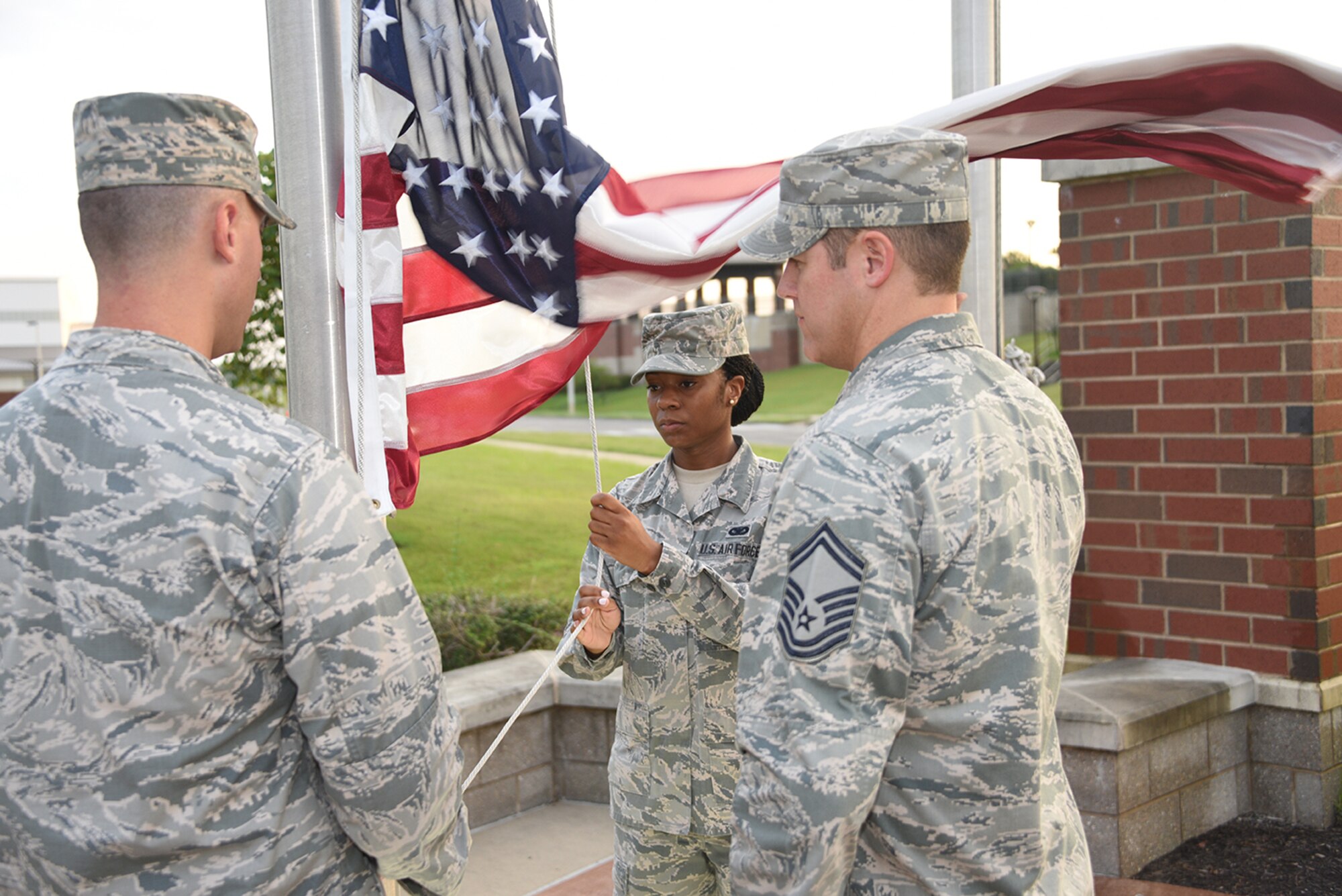 Senior Airman Chelcee Arnold lowers the flag With Lieutenant Matthew Begin and Senior Master Sergeant Matthew Smith during the Retreat Ceremony at Memphis Air National Guard Base on August 7, 2016. (U.S. Air National Guard photo by Master Sergeant Danial Mosher/Released)