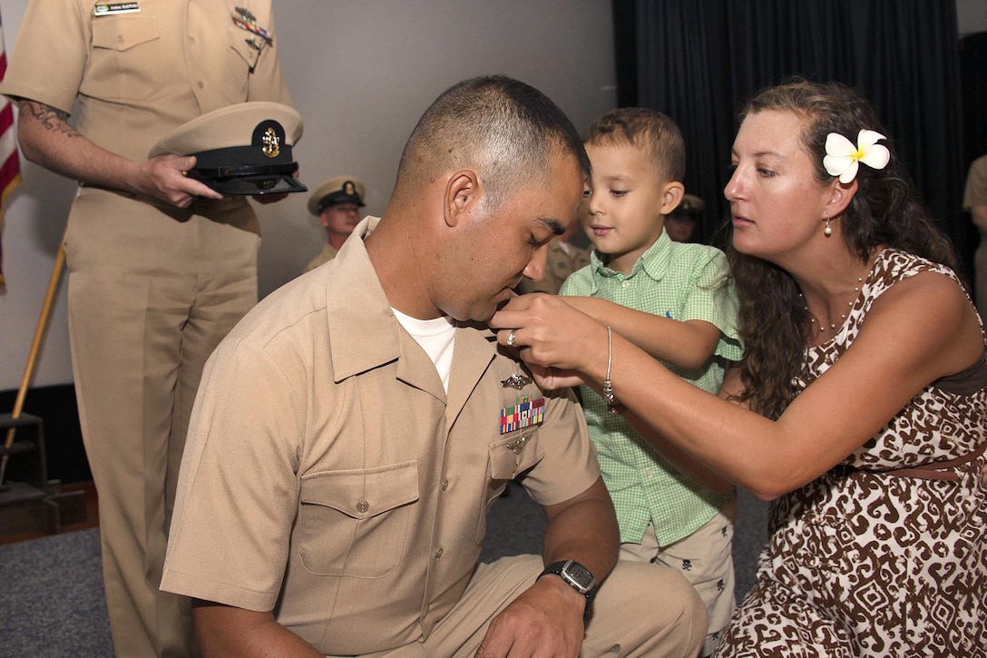 Newly promoted Navy Chief Petty Officer Joseph Scott Rios is pinned by his wife, Desiree, and son, Phoenix, during a chief petty officer pinning ceremony at Sharkey Theatre at Joint Base Pearl Harbor-Hickam, Pearl Harbor, Hawaii, Sept. 16, 2016. Rios is an electronics technician. Navy photo by Petty Officer 2nd Class Shaun Griffin