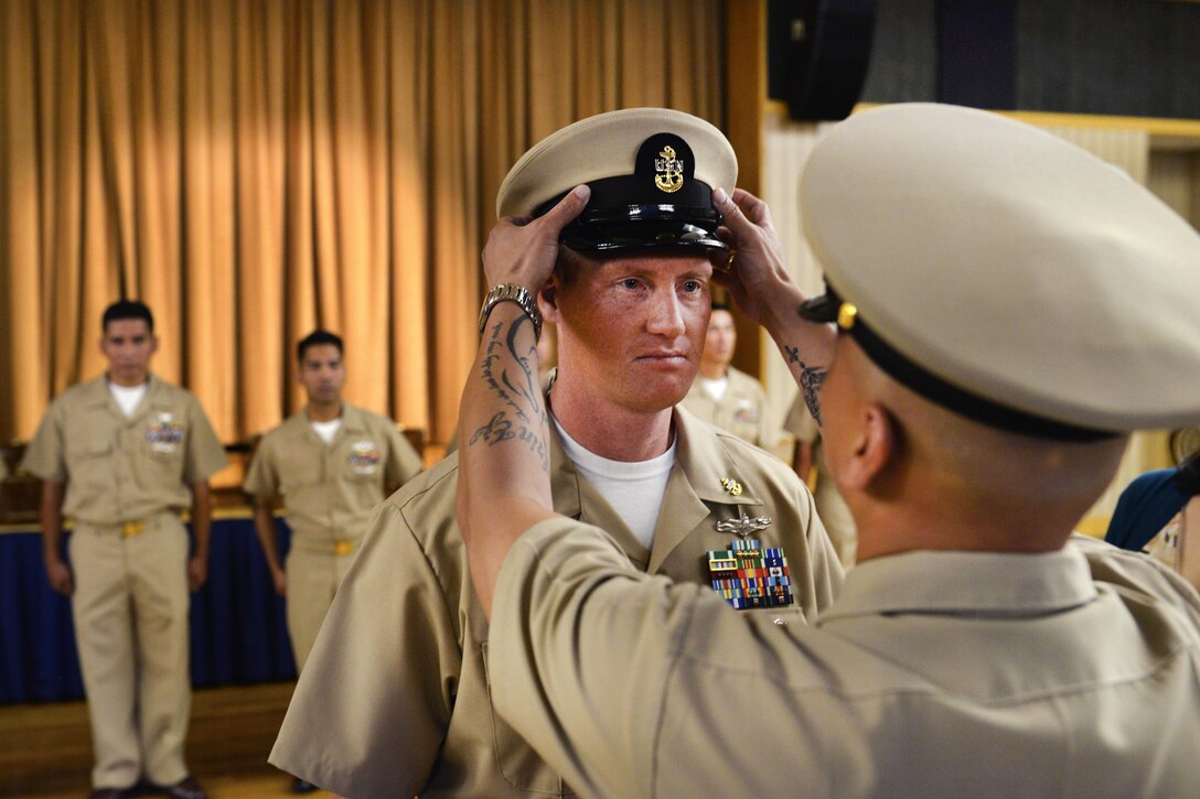 Navy Chief Yeoman Kenneth Vinoya, right, places a chief petty officer combination cover on the head of newly promoted Navy Chief Petty Officer Chief Thomas Zacher during a chief petty officer pinning ceremony at Naval Air Facility Misawa, Japan, Sept. 16, 2016. Zacher is an information systems technician. Navy Photo by Petty Officer 2nd Class Samuel Weldin