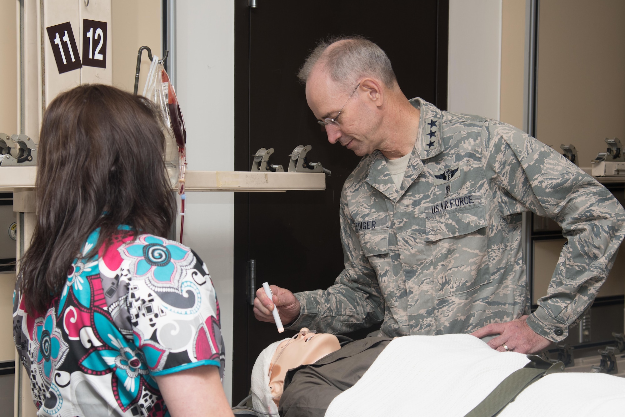 Jamie Gujski, 51st Medical Group simulation operator, gives Lt. Gen. (Dr.) Mark A. Ediger, Surgeon General of the Air Force, Headquarters U.S. Air Force, Washington, D.C., a medical simulation briefing Sept. 14, 2016, at Osan Air Base, Republic of Korea. The manikin, simulating an injured service member, is used by 51st MDG personnel to better assess injuries quickly and efficiently during contingency operations. (U.S. Air Force photo by Senior Airman Dillian Bamman)