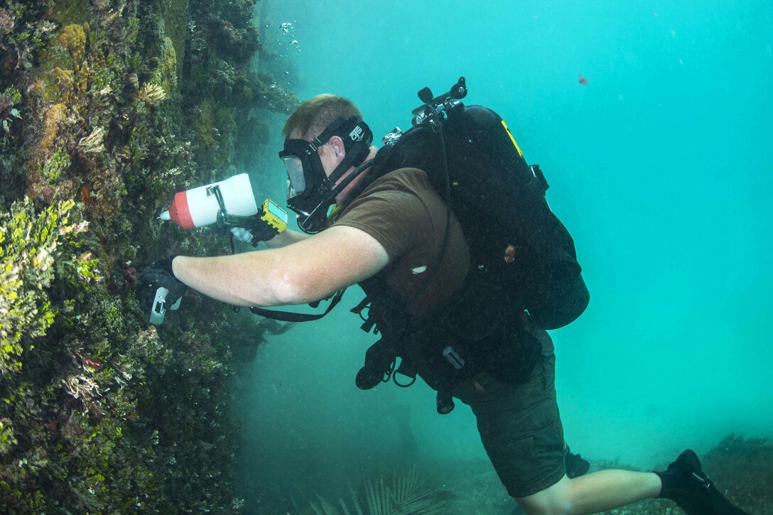 Navy Petty Officer 1st Class David Miller tests the density of the metal pylons on a pier during exercise Valiant Shield 2016 in Kwajalein, Marshall Islands, Sept. 16, 2016. Miller is a steelworker assigned to Underwater Construction Team 2. Navy photo by Petty Officer 2nd Class Daniel Rolston 