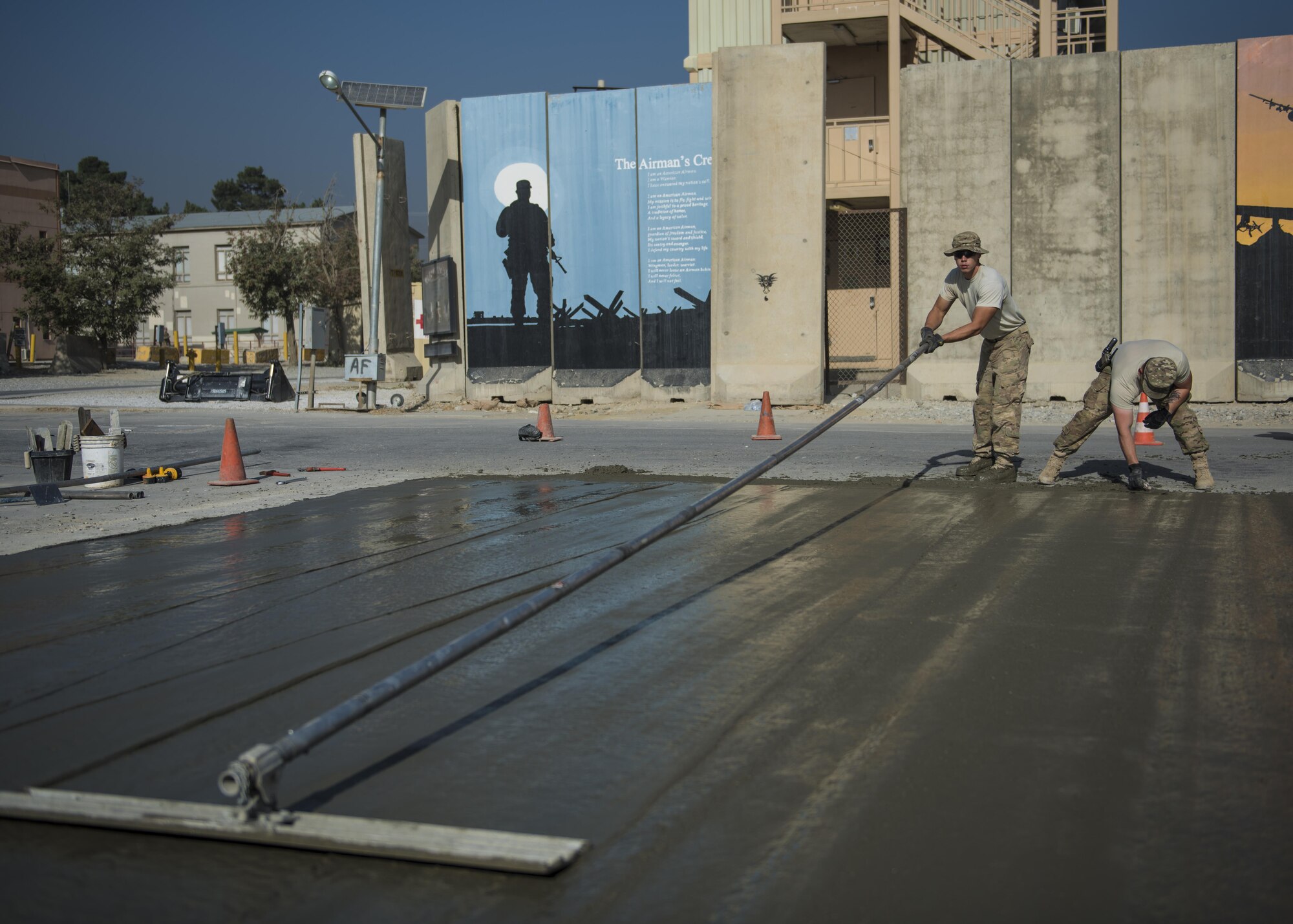 Staff Sgt. Casey Epps, 455th Expeditionary Civil Engineer Squadron pavements and equipment, uses a bull float to push down rocks into concrete mixture, Bagram Airfield, Afghanistan, Sept. 19, 2016. A bull float is used after the surface has been leveled using a screed. It removes imperfections floating on the top surface of the concrete. (U.S. Air Force photo by Senior Airman Justyn M. Freeman)