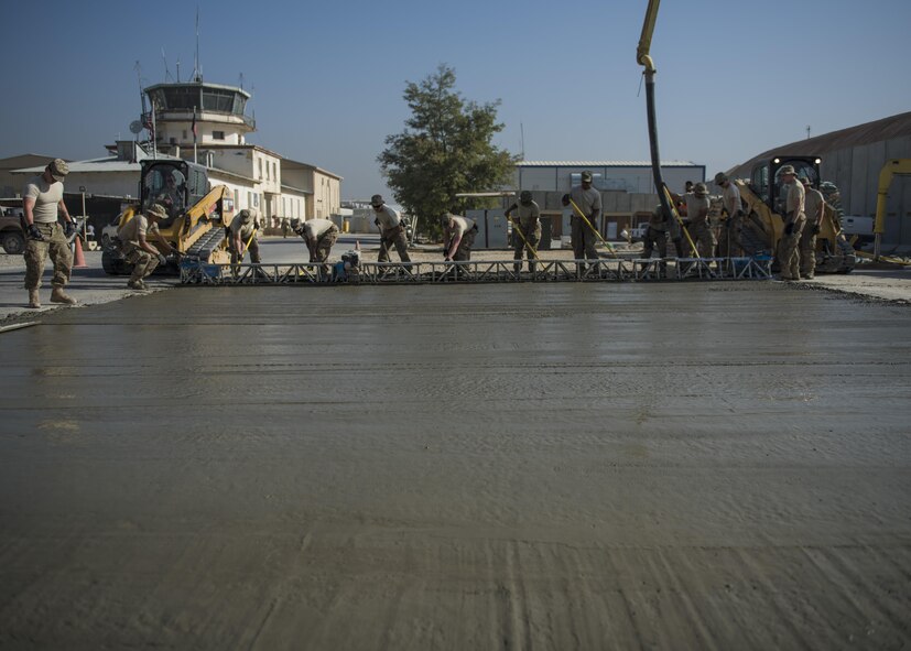 The 455th Expeditionary Civil Engineer Squadron accompanied by volunteers from various base units, leveled out concrete mixture using a screed, Bagram Airfield, Afghanistan, Sept. 19, 2016. The crew helped smooth out the concrete mixture manually before an aluminum screed past over to complete the process. The concrete mixture is being used to construct a parking lot. (U.S. Air Force photo by Senior Airman Justyn M. Freeman)