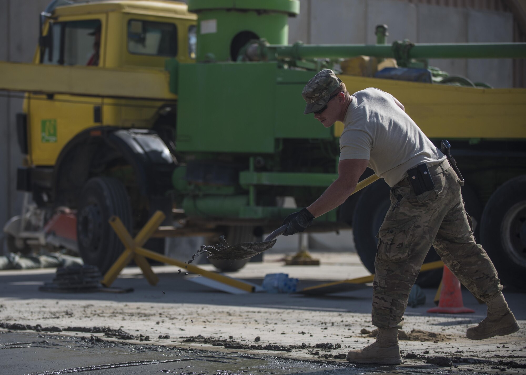 Staff Sgt. Casey Pentecost, 455th Expeditionary Civil Engineer Squadron pavements and equipment, shovels concrete mixture, Bagram Airfield, Afghanistan, Sept. 19, 2016. Excess wet concrete is cut from the outside of the foundation to bring the top surface of a slab to the proper grade and smoothness. (U.S. Air Force photo by Senior Airman Justyn M. Freeman)