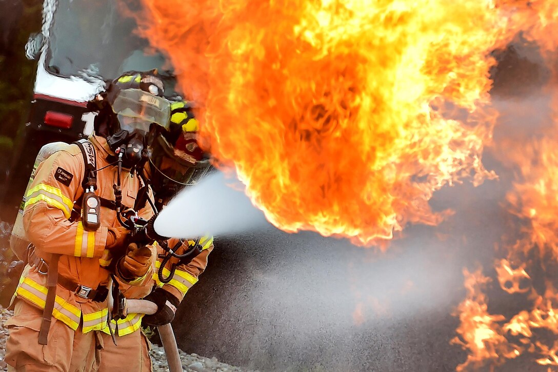 Air Force Senior Airman Larry Kyles, left, and Tech Sgt. Sean Armstrong spray down a simulated aircraft fire during firefighting training at Joint Base Elmendorf-Richardson, Alaska, Sept. 14, 2016. Air Force photo by Justin Connaher  