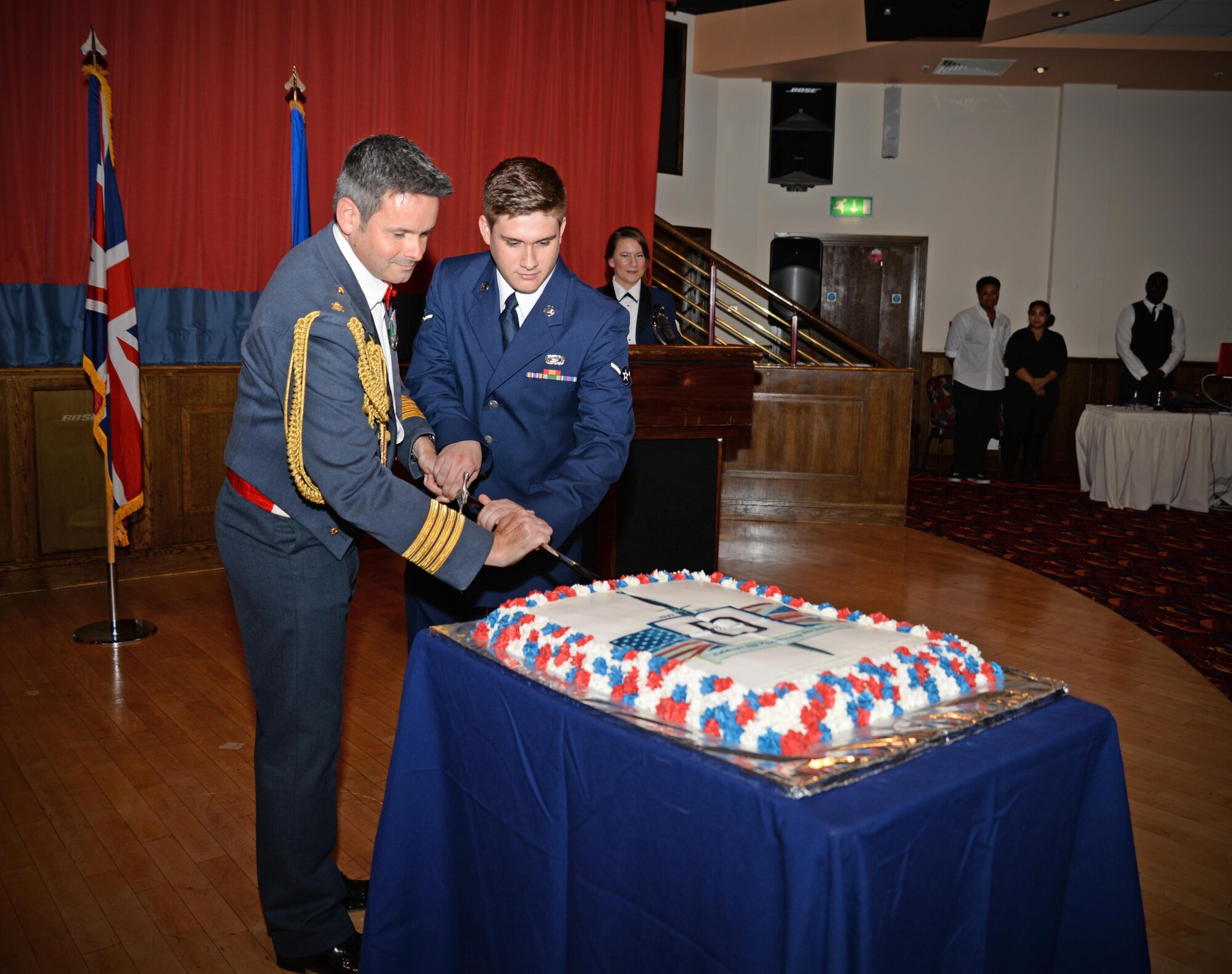 Royal Air Force Group Captain Richard Davies, left, RAF Marham Station Commander, and U.S. Air Force Airman Dylan Aubrey, 100th Force Support Squadron customer service apprentice, cut a cake during the Air Force Ball as part of opening of the ceremony Sept. 17, 2016, on RAF Mildenhall, England. Individuals chosen to cut the cake are traditionally those with the least and the greatest amount of time in service. (U.S. Air Force photo by Senior Airman Christine Halan)