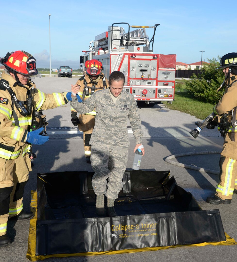 Firefighters from the 6th Civil Engineer Squadron escort Senior Airman Sarah Eby, center, fuels system Repairman apprentice with the 6th Maintenance Squadron, through decontamination during an Emergency Management exercise at MacDill Air Force Base, Fla., Sept. 13, 2016. Eby acted as an Airman injured from a vehicle accident during the exercise. (U.S. Air Force photo by Senior Airman Vernon L. Fowler Jr.)